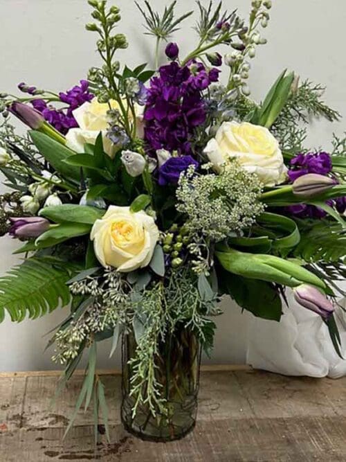 Flower arrangement with rich purple blooms and greenery in a glass vase